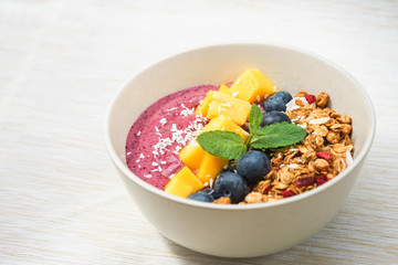Handmade Bowl healthy tasty breakfast of yogurt, smoothie with granola, nuts, mango and berries.