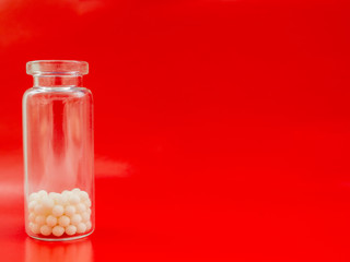 Homeopathic globules and glass bottle on red background. Homeopathic Medicine