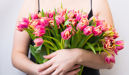 a large bouquet of pink tulips in the hands of a girl