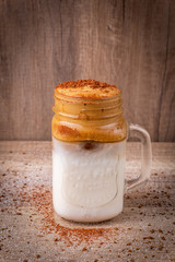 Obraz na płótnie Canvas Iced Dalgona Coffee, a trendy fluffy creamy whipped coffee on a wooden table