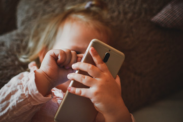Beautiful little girl watching cartoons on a smartphone. Video communication. Online call to...