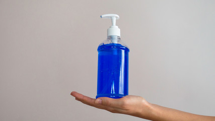 Hand sanitizer pump bottle, washing gel, alcohol gel in hand on a gray background.