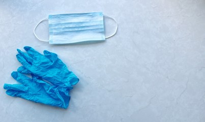 Medical mask and blue medical gloves on a blue background.