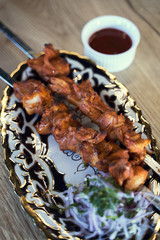Preparation of shish kebab bbq.  Grilled pork on a white plate on a wooden table. Grilled pork skewers - 341416112
