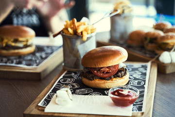 Craft beef burger and french fries on wooden table isolated on black background. Hamburgers and French fries on the wooden tray. - 341418532