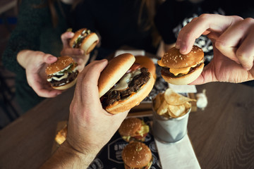 Group of friends  eating at fast food - Happy people partying and eating in home garden - Young active adults in a picnic area with burgers. Hands holding fresh delicious burgers   - 341418736