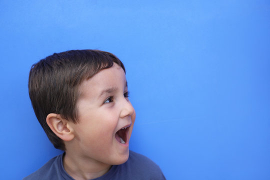 ni&ntilde;o de perfil en un fondo azul con la boca abierta gritando con espacio para texto
