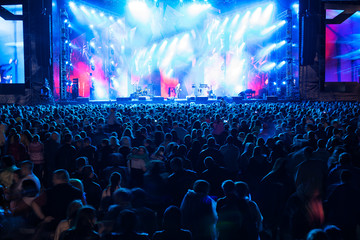 silhouettes of concert crowd in front of bright stage lights.