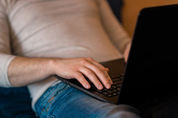 Naklejka premium Man using laptop in a hotel room or home bedroom. Distance learning during the Covid-19 pandemic. freelasner, distant work