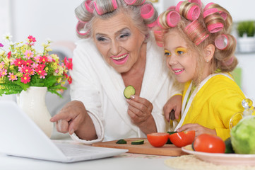 Close up portrait of senior woman and girl using laptop