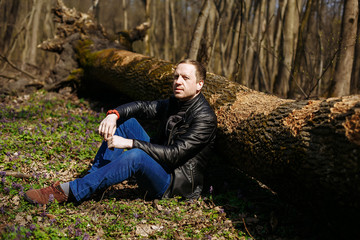 Naklejka na ściany i meble a man sits under a fallen tree in the forest