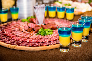 Delicious Ukrainian snacks at the wedding. Meat sliced on a plate. Sausage and Ukrainian vodka.