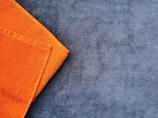 grey terry towel. orange towel on a gray background.