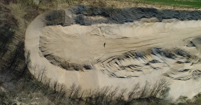 Aerial footage of a human walking down a pile of aggregates