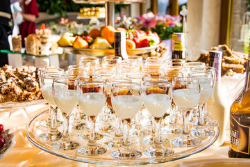 Candy bar with tasty desserts and appetizers at wedding reception. Decorated with flower compositions and candles. Sweet food, dessert, buffet, catering table, restaurant.
