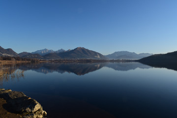 Alserio lake Como Italy - mountain reflected on the water - blue sky - Lago di Alserio