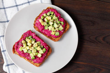 Variation of healthy toasts with avocado beetroot and whole wheat rye bread on a plate.  Delicious snacks, avocado sandwiches. Food composition, tasty vegan food. Close up, top view