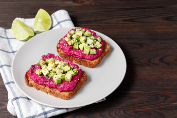 Variation of healthy rye toasts with avocado and beetroot on a plate. Delicious snacks, avocado sandwiches. Food composition, tasty italian meal. Close up, top view