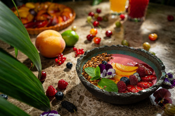 Fruit healthy muesli with peaches strawberry almonds and blackberry in clay dish with yogurt on wooden kitchen table