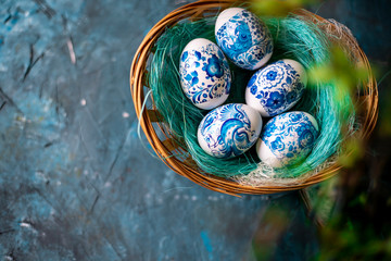 Easter eggs in a straw basket on a blue background.
