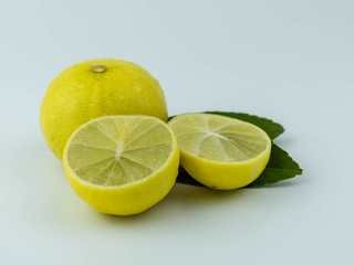 Natural fresh lemon, sliced in half and green leaves, isolated on a white background