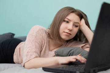 The teenager lies on a bed while studying for the exam in the room.