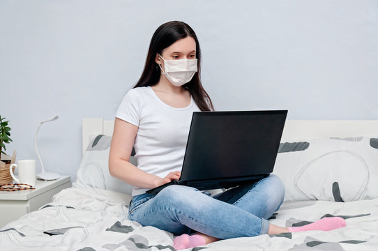 Work Home or Distance Online Learning on Quarantune. Woman in Protective Face Mask Remotely Working on Bed Using Laptop