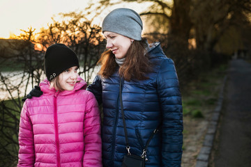 Fototapeta premium Woman with her daughter walking by the river and talking and rejoicing that they reconciled after an argument and clarifying relationships