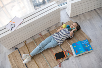 Cheerful girl with an apple and smartphone lying on floor.