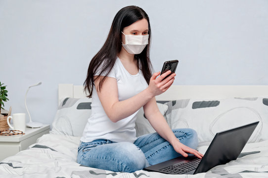Work Home or Distance Online Learning on Quarantune. Woman in Protective Face Mask Remotely Working on Bed Using Laptop and Talking on Phone