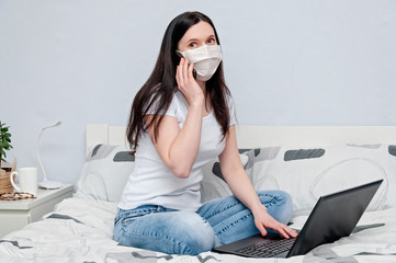 Work Home or Distance Online Learning on Quarantune. Woman in Protective Face Mask Remotely Working on Bed Using Laptop and Talking on Phone