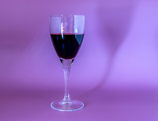 A glass of red wine with reflection isolated on a purple background