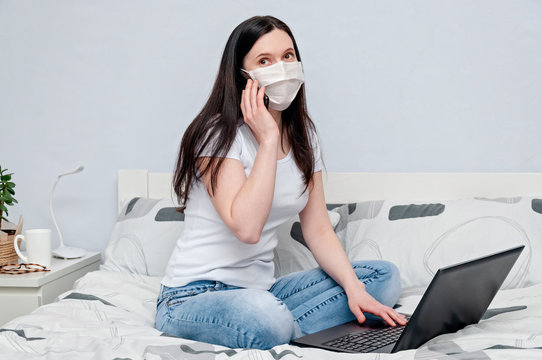 Work Home or Distance Online Learning on Quarantune. Woman in Protective Face Mask Remotely Working on Bed Using Laptop and Talking on Phone