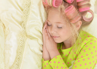 Lovely little girl with pink curlers sleeping