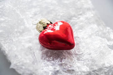 Decorative glass heart on the plastic pack. Concept of glass love. Concept of health. For telling. Magazine, blog.