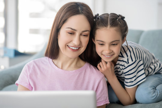 Happy and beautiful mother with daughter looking at laptop.