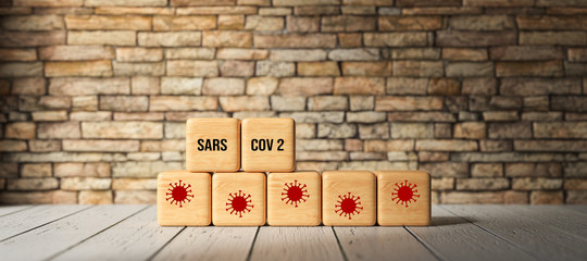 Fototapeta na wymiar cubes with text SARS COV 2 and virus icons in front of a brick wall on a wooden floor