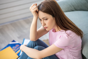 Long haired sad woman holding hand to head.