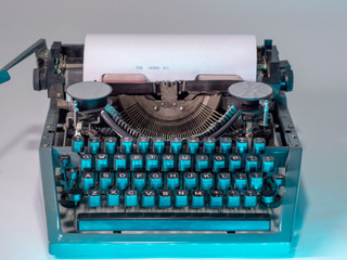 Old vintage typewriter, retro machine with white sheet of paper and typed text.