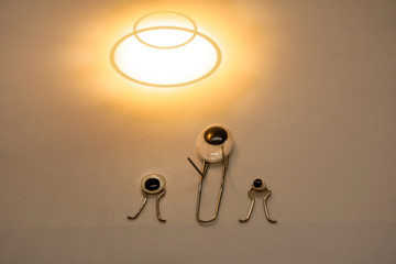 creative idea. 3 metal paper clips with eyes depicting aliens looking at a flying saucer. white background. empty space.