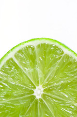 Fototapeta na wymiar A close up of a single slice of green lemon over a white background.