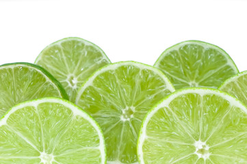 Various slices of green lemon over a white background.