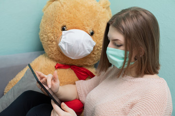 The young girl learns for the exam together with the big teddy bear. They are both wearing...