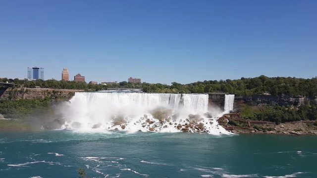 The famous waterfall of Niagara Falls, a popular place among tourists from all over the world. View from the Canada. In the image waterfall and boats can be seen at the same time.