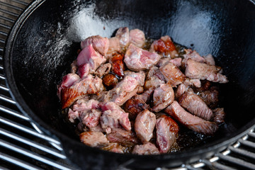 Pieces of lamb with onion are fried in boiling oil on the fire. As a stage in the preparation of...