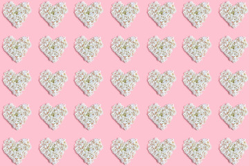 the floral concept in pastel colors. pattern made hearts of white hydrangea flowers on a pink background. flat lay, top view