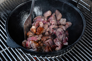 Pieces of lamb with onion are fried in boiling oil on the fire. As a stage in the preparation of...