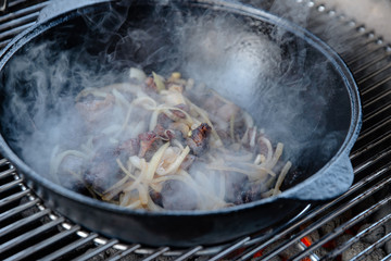 Pieces of lamb with onion are fried in boiling oil on the fire. As a stage in the preparation of...