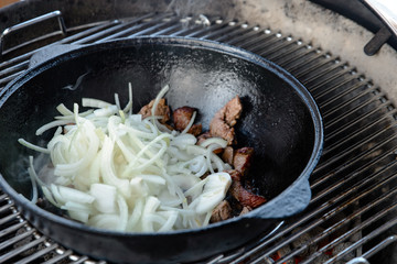 Pieces of lamb with onion are fried in boiling oil on the fire. As a stage in the preparation of...