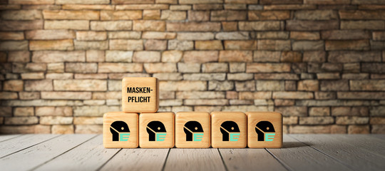 cubes with German message FACE MASK DUTY in front of a brick wall background